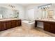 Spacious bathroom featuring dual sinks, vanity, glass block window, and soaking tub at 13221 W Rincon Dr, Sun City West, AZ 85375