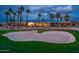 Tranquil view from the golf course featuring a sand trap, palms, and stunning homes in the background at 13221 W Rincon Dr, Sun City West, AZ 85375