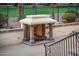 An outdoor fireplace with stone pillars provides a cozy space for gathering in the backyard at 13221 W Rincon Dr, Sun City West, AZ 85375