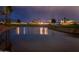 Serene pond reflecting community homes and palm trees at twilight on the lush golf course at 13221 W Rincon Dr, Sun City West, AZ 85375