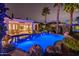 Stunning backyard pool with rock features, palm trees, and a covered patio perfect for relaxing at 13221 W Rincon Dr, Sun City West, AZ 85375