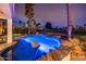 A beautifully lit pool and spa with integrated bar stools, surrounded by lush landscaping at 13221 W Rincon Dr, Sun City West, AZ 85375