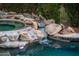An inviting pool features a rock waterfall and jacuzzi, surrounded by lush greenery at 13221 W Rincon Dr, Sun City West, AZ 85375