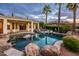 Backyard pool area with a rock waterfall, spa, and lounge chairs surrounded by palm trees at 13221 W Rincon Dr, Sun City West, AZ 85375