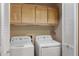 Well-lit laundry room features washer, dryer, and overhead wooden cabinets for convenient storage at 13227 N Mimosa Dr # 107, Fountain Hills, AZ 85268