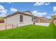 Backyard view showcasing green grass, a paved patio area, neutral paint, and a property fence, under a blue sky at 13603 W Remuda Dr, Peoria, AZ 85383