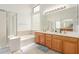 Bathroom featuring a double sink vanity, soaking tub with glass block window, and a separate glass-enclosed shower at 1805 E Sagebrush St, Gilbert, AZ 85296
