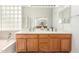 Bathroom featuring double sinks with wood cabinets and an elegant soaking tub with a privacy-glass window at 1805 E Sagebrush St, Gilbert, AZ 85296