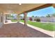 A covered patio leads to a backyard featuring a lush green lawn and mature shrubs at 2077 N Lake Shore Dr, Casa Grande, AZ 85122