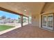 Covered patio featuring stone flooring, view of community pool, and manicured lawn at 2077 N Lake Shore Dr, Casa Grande, AZ 85122