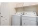 The laundry room features a set of white washer and dryer machines and a shelf for storage at 2600 E Springfield Pl # 10, Chandler, AZ 85286