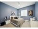 Comfortable bedroom with blue walls, ceiling fan, art and a well-appointed queen bed and side tables at 3244 E Daley Ln, Phoenix, AZ 85050