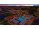 Aerial view showcases the community pool, tennis courts, and surrounding neighborhood at sunset, highlighting community amenities at 4432 E Carmel Ave, Mesa, AZ 85206