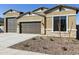 Beautiful home featuring a three-car garage, beige stucco, stone accents, and well-kept gravel landscaping at 4946 W Weeping Willow Way, Laveen, AZ 85339