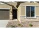 Close-up of a home's entrance showing the stucco exterior, stone accents, and a well-maintained yard at 4946 W Weeping Willow Way, Laveen, AZ 85339