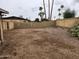 Spacious empty backyard surrounded by a block fence with tall palm trees in the background at 5220 E Winchcomb Dr, Scottsdale, AZ 85254