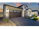 Charming single-Gathering home featuring stone accents, a dark brown garage, and brick paved driveway at 5748 E Sierra Morena St, Mesa, AZ 85215