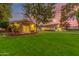 Charming home exterior featuring a manicured lawn, mature trees, and inviting outdoor lighting at dusk at 5801 E Exeter Blvd, Phoenix, AZ 85018