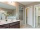 Bathroom with double sink vanity, large mirror, tub and shower behind an open doorway at 6853 E Posada Cir, Mesa, AZ 85212