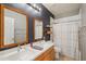 Bathroom featuring double vanity, decorative mirrors, accent wall, and a shower with curtain at 8004 W Robin Ln, Peoria, AZ 85383