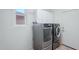 Bright laundry room with modern washer and dryer units, white walls, and tiled floor at 8004 W Robin Ln, Peoria, AZ 85383