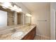 Bathroom with double sinks, granite countertops, wood cabinets, and a walk-in shower at 8625 E Belleview Pl # 1012, Scottsdale, AZ 85257
