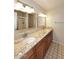Bathroom with double sinks, granite countertops, wood cabinets, and a walk-in shower at 8625 E Belleview Pl # 1012, Scottsdale, AZ 85257