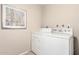 Efficient laundry area with white appliances and clean, neutral walls at 10547 W Coggins Dr, Sun City, AZ 85351