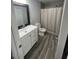 Clean bathroom with a white vanity, a walk-in shower with curtain, and modern wood-look floors at 1132 E 9Th Pl, Casa Grande, AZ 85122