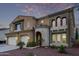 Two-story home features a distinctive architecture, desert landscaping, and a welcoming arched entryway at 12910 W Tuckey Ln, Glendale, AZ 85307