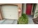 Close up of a two-car garage and a red front door flanked by greenery at 12910 W Tuckey Ln, Glendale, AZ 85307