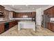 Well-equipped kitchen featuring an island, granite countertops, and dark wood cabinets at 12910 W Tuckey Ln, Glendale, AZ 85307