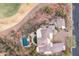 Aerial view shows luxurious home with pool, outdoor seating, and tile roof next to a golf course in desert landscape at 15956 E Tombstone Trl, Fountain Hills, AZ 85268