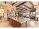 Open kitchen and living space with beamed ceilings, a granite island, and an inviting fireplace at 15956 E Tombstone Trl, Fountain Hills, AZ 85268