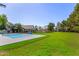 Expansive backyard with a pickleball court, pool, lush green lawn, mature trees, and a residence at 1632 S Alba Cir, Mesa, AZ 85204