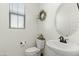 Cozy powder room with a pedestal sink, round mirror, decorative wreath, and a window for natural light at 1679 E Dogwood Ln, Gilbert, AZ 85295