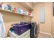 Functional laundry room equipped with a modern washer and dryer, ample shelving, and an ironing board at 17005 S Coleman St, Phoenix, AZ 85045
