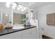 Bright bathroom with white cabinetry, a dark countertop, and a large mirror with vanity lighting at 1715 W Carol Ave, Mesa, AZ 85202