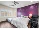 Main bedroom suite with unique purple accent wall, wood floors, and massage chair next to a window at 17545 W Lilac St, Goodyear, AZ 85338
