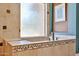 Relaxing soaking tub with decorative tile and a frosted glass window at 22521 N 60Th Ave, Glendale, AZ 85310