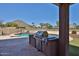 Outdoor kitchen area equipped with a grill, set against a backdrop of a sparkling swimming pool at 22521 N 60Th Ave, Glendale, AZ 85310