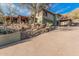 View of a green house with red tile roof, driveway, and desert landscaping, blending with the surrounding natural landscape at 3201 N 91St St, Mesa, AZ 85207