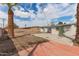 Large backyard with block fence, concrete patio, and mature trees under a blue partly cloudy sky at 3707 W Elm St, Phoenix, AZ 85019