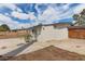 Exterior side view of home with a fenced yard, concrete patio, and mature trees under a partly cloudy sky at 3707 W Elm St, Phoenix, AZ 85019
