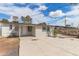 Rear exterior view shows door, windows, concrete patio, and mature trees under a partly cloudy sky at 3707 W Elm St, Phoenix, AZ 85019