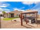 A backyard with gravel, artificial grass, decorative cacti, gazebo, and hot tub under a blue sky at 39984 W Hopper Dr, Maricopa, AZ 85138