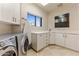 Bright laundry room featuring a modern washer and dryer, white cabinetry, and a window for natural light at 41823 N 111Th Pl, Scottsdale, AZ 85262