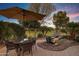 Landscaped backyard with patio, outdoor seating, and lush greenery, with lit water feature at 42920 W Kingfisher Dr, Maricopa, AZ 85138