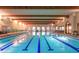 Stunning indoor pool with clear blue water, wooden beams, and arched windows at 42920 W Kingfisher Dr, Maricopa, AZ 85138