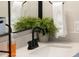 Close-up of a well-appointed bathroom sink featuring black fixtures and a charming decorative plant at 4617 E La Puente Ave, Phoenix, AZ 85044